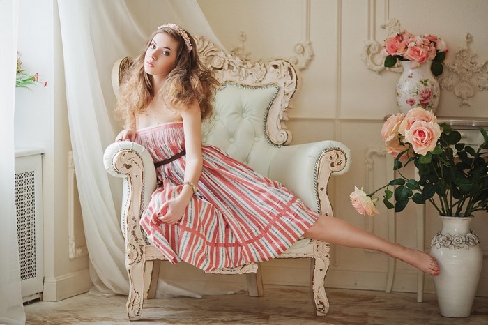 Woman in striped dress sitting in ornate chair with roses