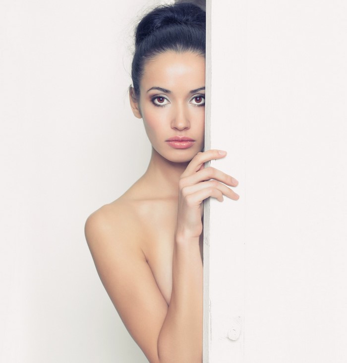 Woman peeking from behind a white surface