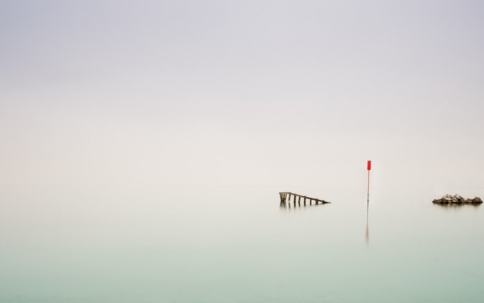 Minimalist seascape with pier, buoy, and rocks