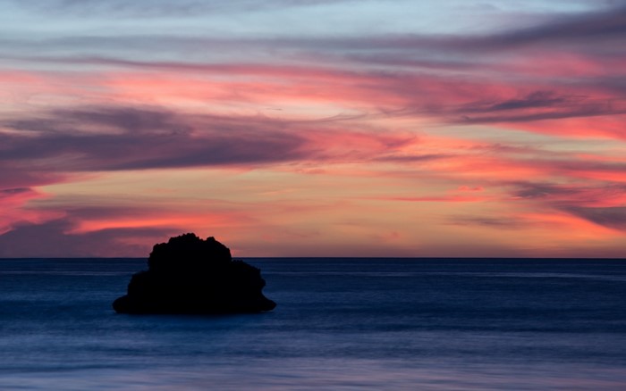 Silhouette of a rock in the sea at sunset