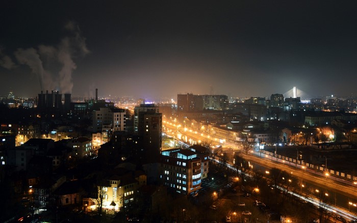Night cityscape with industrial smoke and city lights
