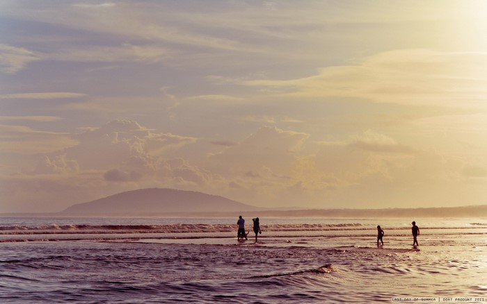 People walking on a beach at sunset