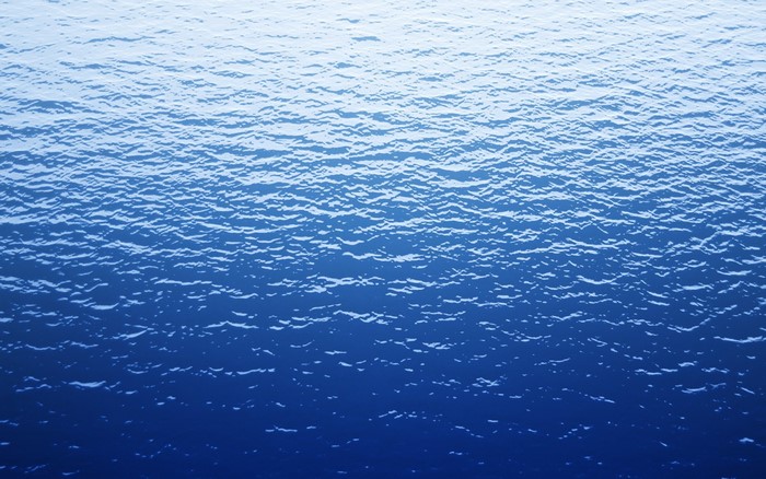 Blue ocean waves with sunlight reflection