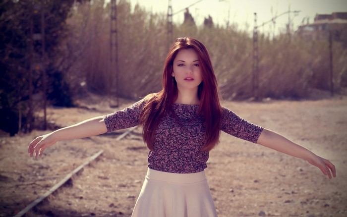 Woman with red hair in a floral top and skirt outdoors