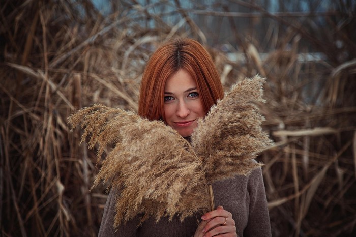 Woman with red hair holding reeds
