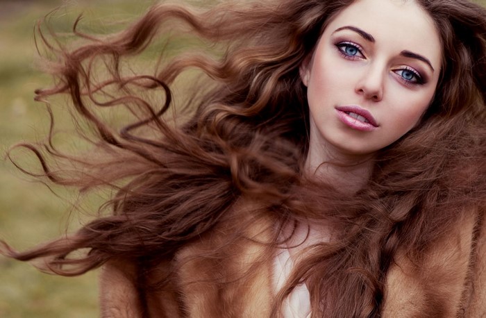 Woman with long brown hair and blue eyes wearing fur