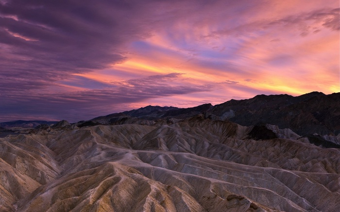 Badlands landscape at sunset with colorful clouds