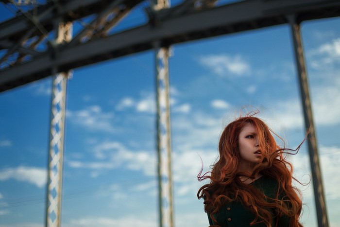 Redhead woman with long hair on a bridge
