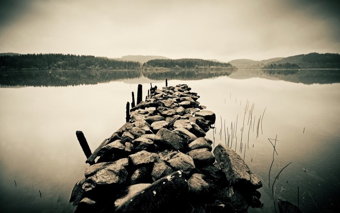 Stone pier on a calm lake with forest reflection
