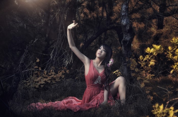 Woman in Red Dress Reaching for Sunlight in Forest