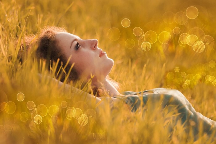 Woman lying in grass with bokeh effect