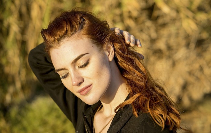 Redhead woman with eyes closed touching her hair