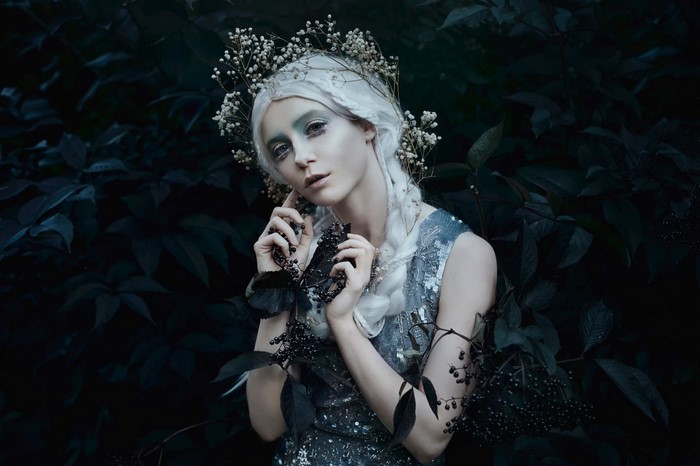Woman with white hair and flower crown in dark forest