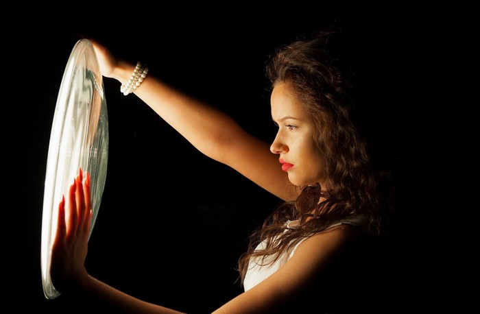 Woman holding a glass disc in the dark