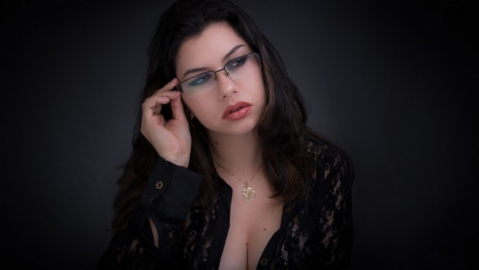 Woman with glasses wearing a black lace shirt