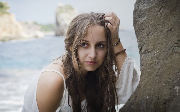 Young woman with long brown hair by the sea