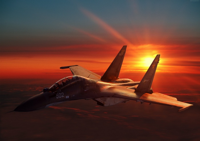Sukhoi Su-30 fighter jet flying at sunset