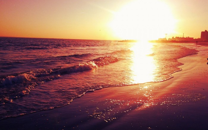 Sunset over the ocean with waves on the beach