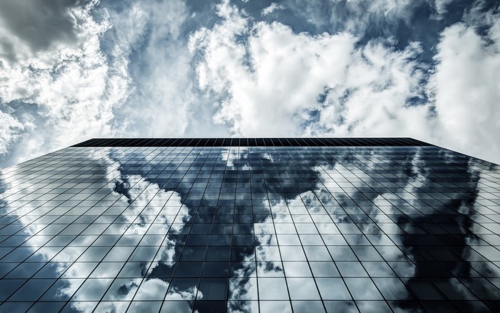 Modern skyscraper facade reflecting clouds in the sky