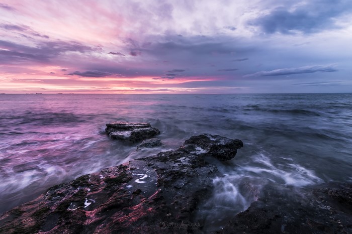 Sunset over the sea with rocks and clouds