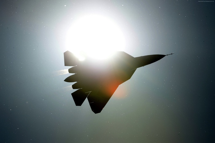 Sukhoi Su-57 fighter jet silhouetted against the sun