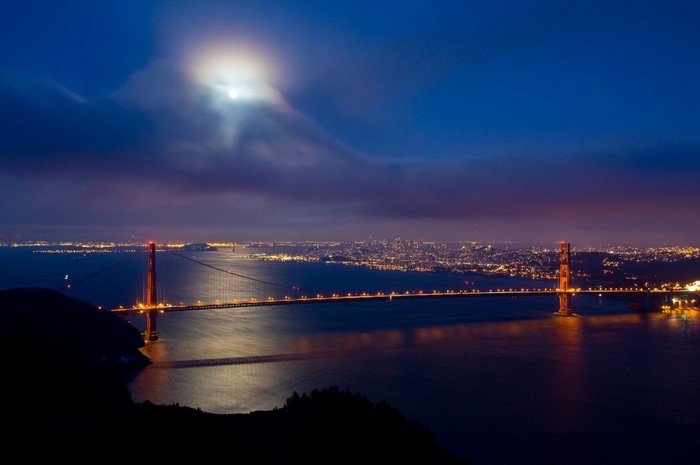 Golden Gate Bridge at night with moon and cityscape