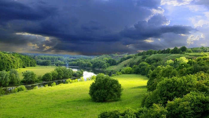 Stormy sky over a green valley with a river