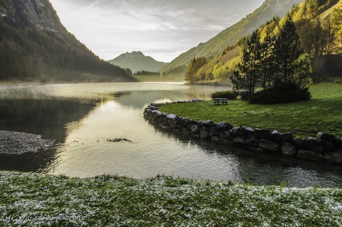Misty lake and mountains at sunrise with a picnic table