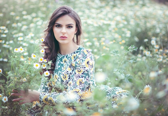 Woman in a floral dress in a field of daisies