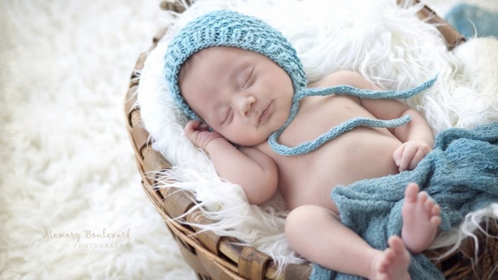Baby sleeping in a basket with a blue hat