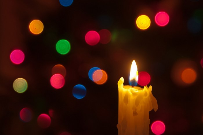 Glowing Candle with Colorful Christmas Bokeh Lights
