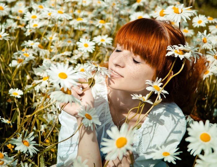 Redhead girl in a field of daisies