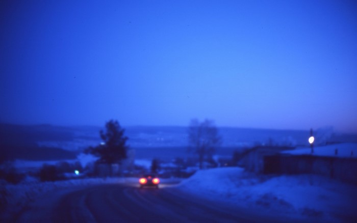 Car driving on a snowy road at dusk