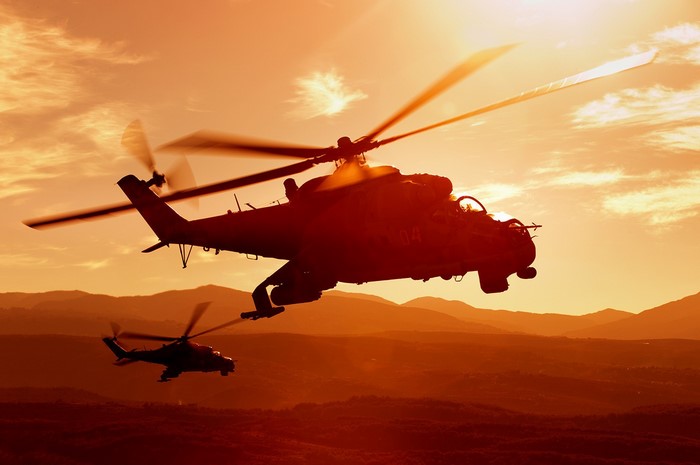 Two Russian Mi-24/Mi-35 helicopters in flight at sunset