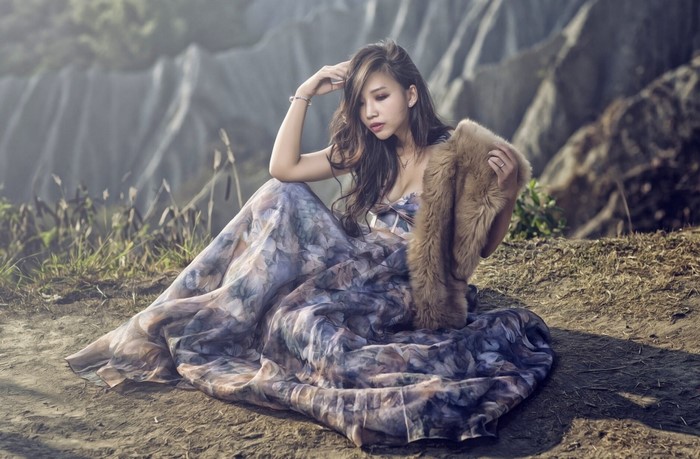 Asian woman in floral dress with fur stole sitting outdoors