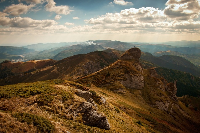 Man standing on a rocky mountain peak overlooking a valley