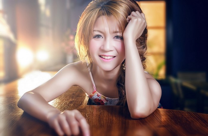 Woman with blonde hair smiling, resting her head on her hand