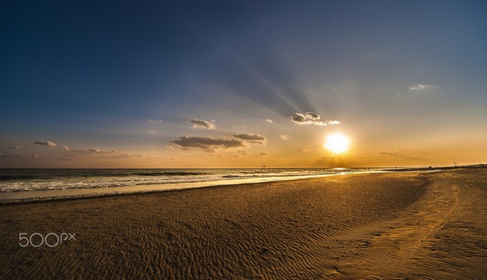Sunset over the ocean with sun rays on the beach