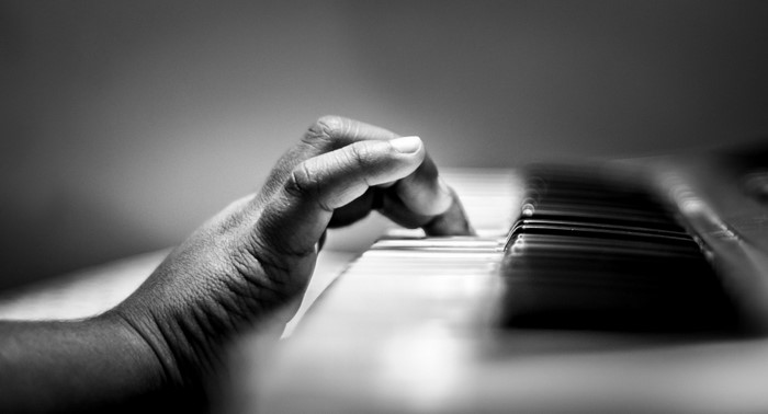 Close-up of a hand playing a piano in monochrome