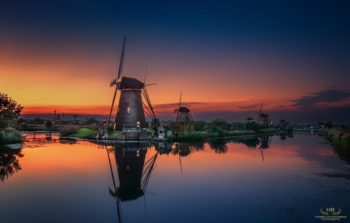 Windmills reflecting in water at sunset