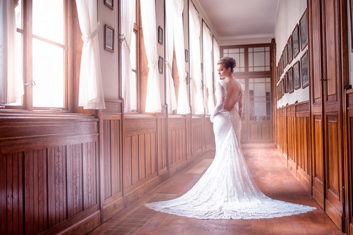 Elegant Bride in Lace Wedding Gown in Sunlit Hallway
