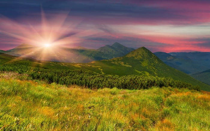 Sunrise over a mountain range with green hills