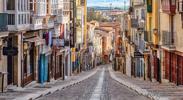 Cobblestone street lined with colorful buildings and balconies
