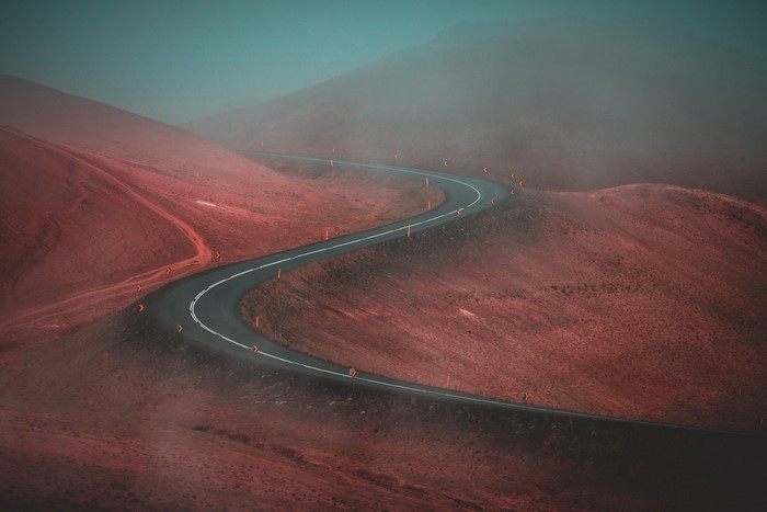 Winding road through red hills in fog