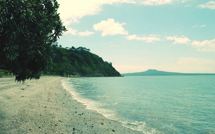 Beach with green hill and distant island