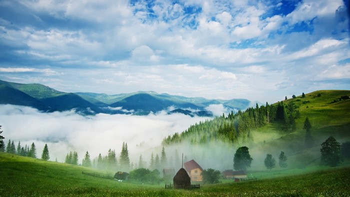 Misty mountain valley with houses and haystacks