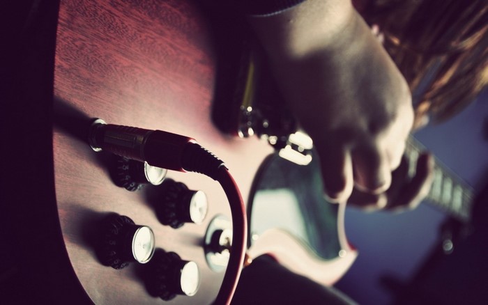Close up of a person playing a red electric guitar