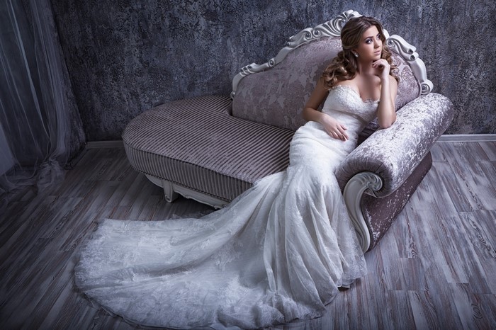 Bride in a white lace gown on a vintage couch