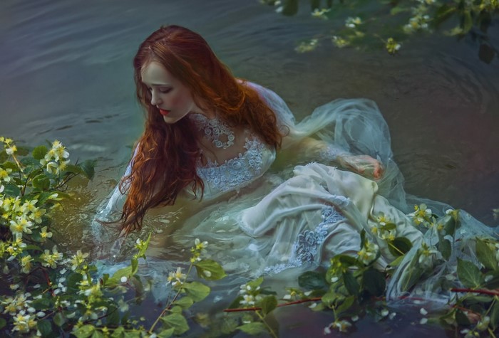 Woman in white dress in water with flowers