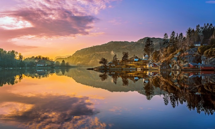 Sunset over a tranquil lake with houses on the shore